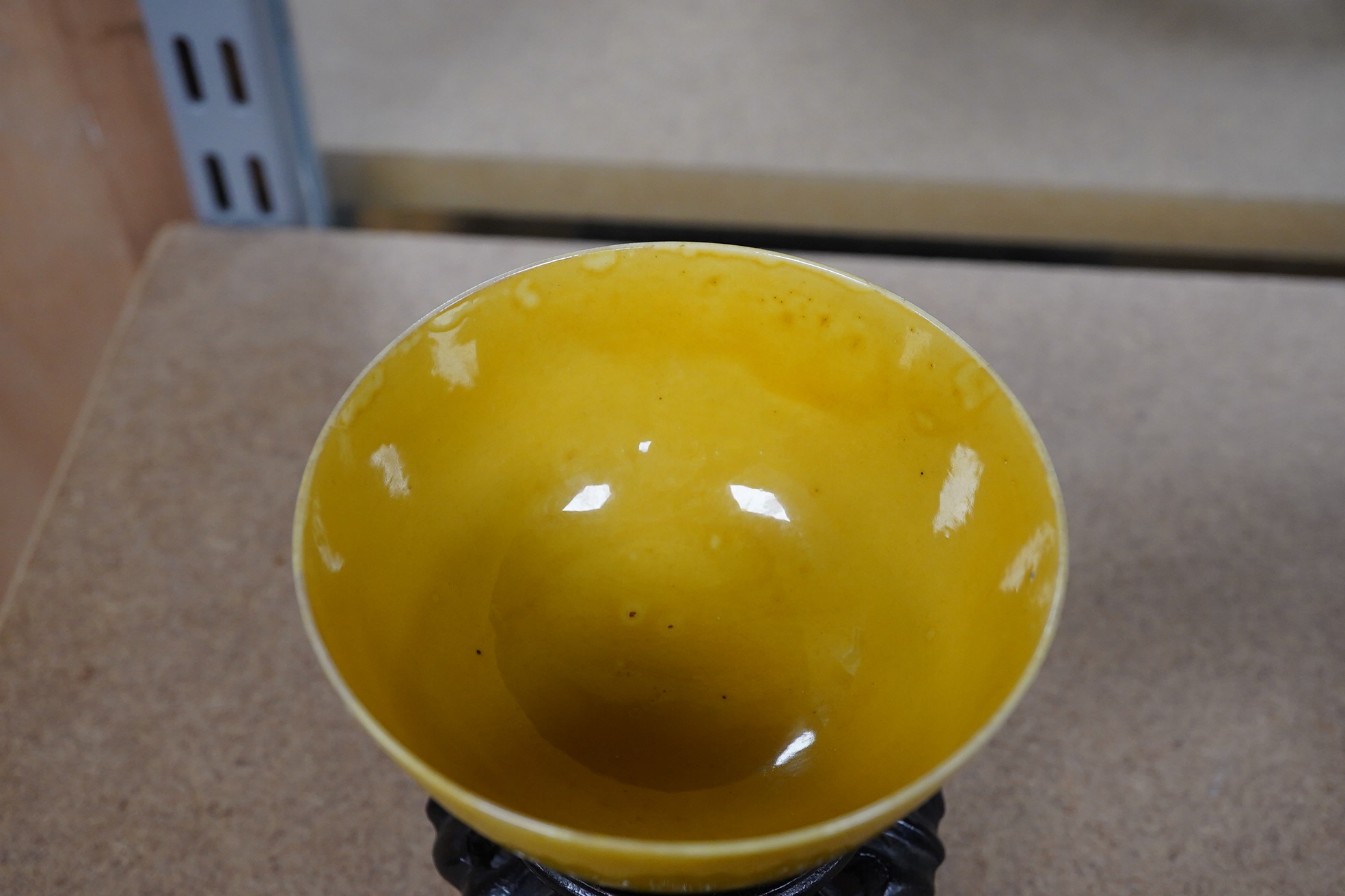 A Chinese yellow glazed teabowl on hardwood stand, 9cm diameter. Condition - fair